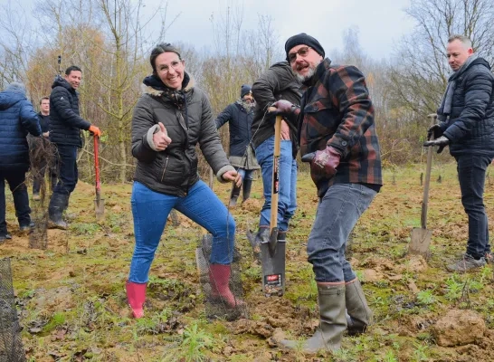 Werknemers van twee verzekeringsbedrijven planten bomen op een domein vlakbij de luchthaven
