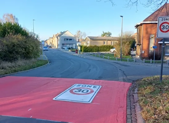 Een rode geschilderde band op de rijweg geeft de uitgebreide zone 30 aan in Peutie bij Vilvoorde