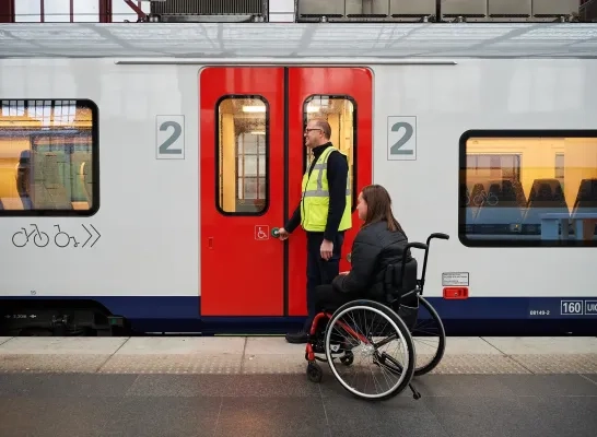 Een treinreiziger met een beperkte mobiliteit krijgt assistentie bij het instappen
