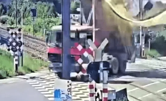 Vrachtwagen rijdt aan spooroverweg in Groot-Bijgaarden met laadbak omhoog tegen bovenleiding 