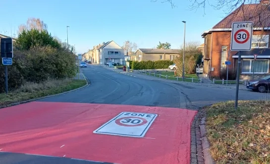 Een rode geschilderde band op de rijweg geeft de uitgebreide zone 30 aan in Peutie bij Vilvoorde