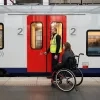 Een treinreiziger met een beperkte mobiliteit krijgt assistentie bij het instappen