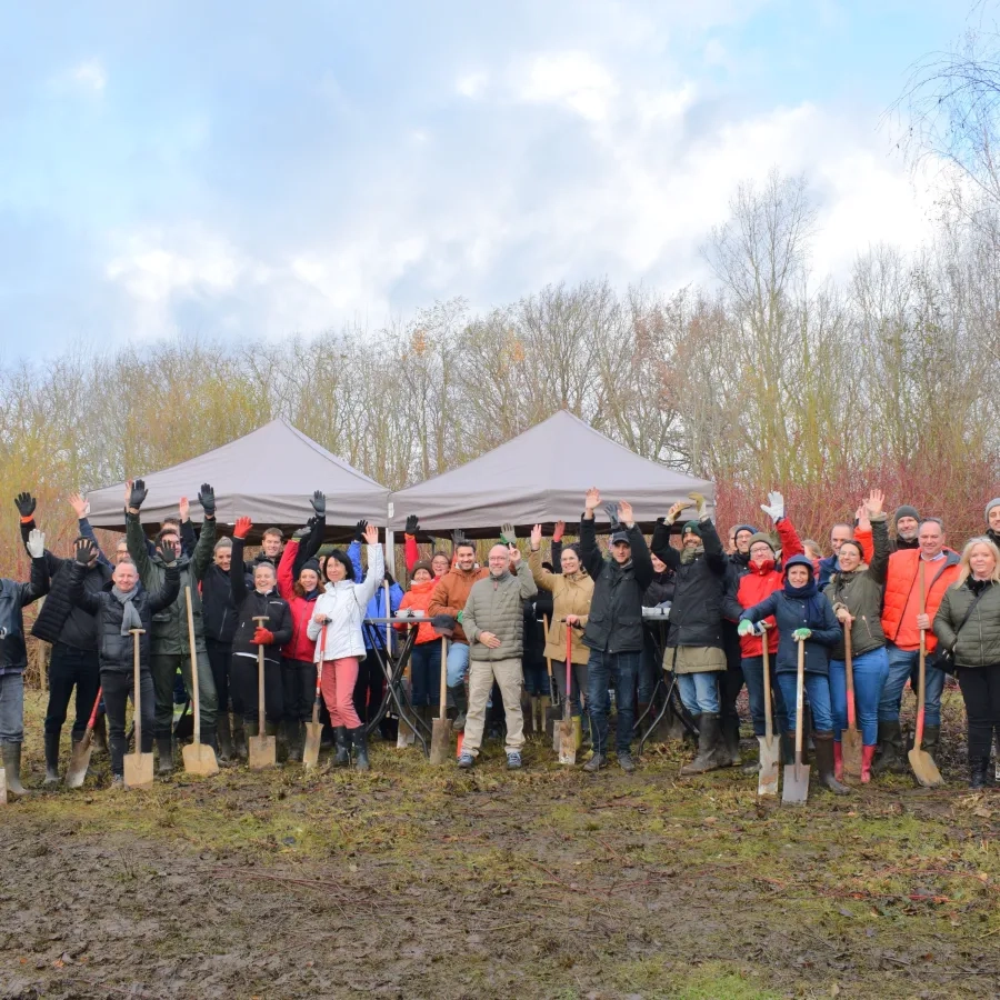Werknemers van twee verzekeringsbedrijven planten bomen op een domein vlakbij de luchthaven