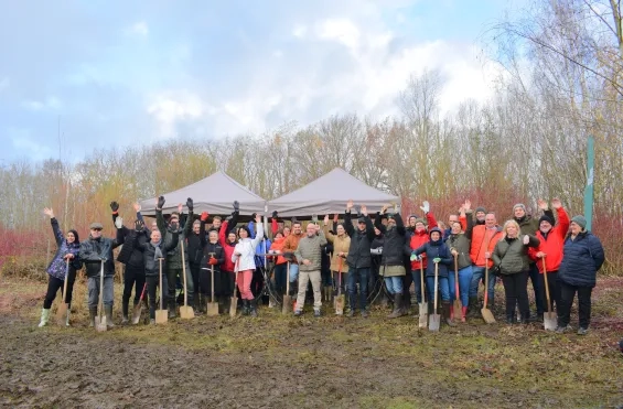 Werknemers van twee verzekeringsbedrijven planten bomen op een domein vlakbij de luchthaven